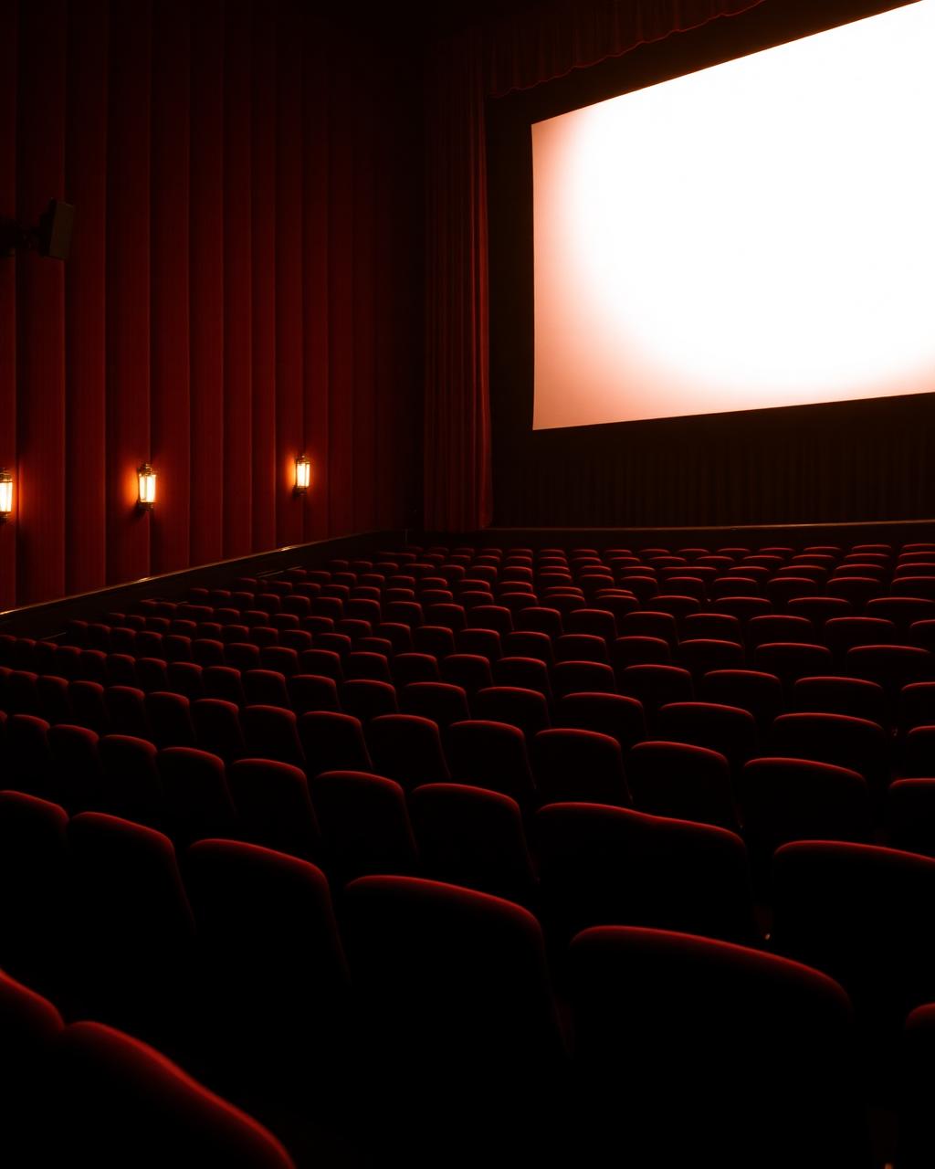 Warmly lit empty cinema auditorium facing a glowing screen